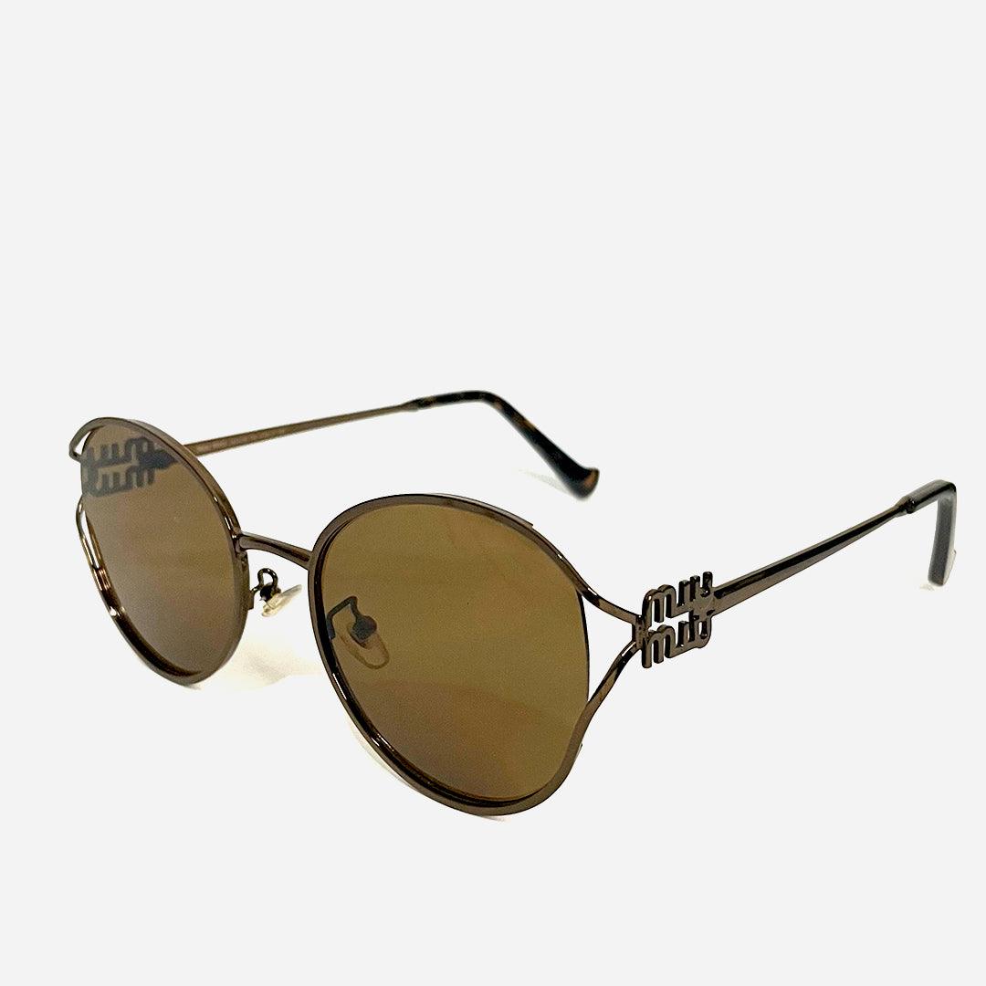 Óculos de sol Desert Gold com armação metálica em tom dourado e lentes espelhadas na cor dourada. Design arredondado e detalhes exclusivos nas hastes, trazendo sofisticação e estilo retrô moderno.