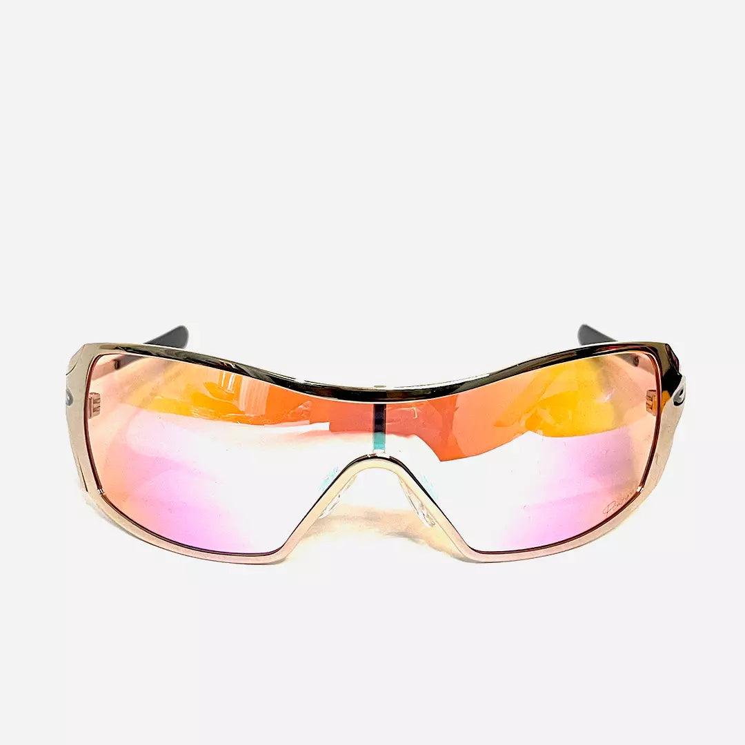 Óculos de sol Dynamic Rose Gold com lentes espelhadas em tons de rosa e dourado, armação envolvente em acabamento metálico dourado. Design moderno e funcional para proteção UV.