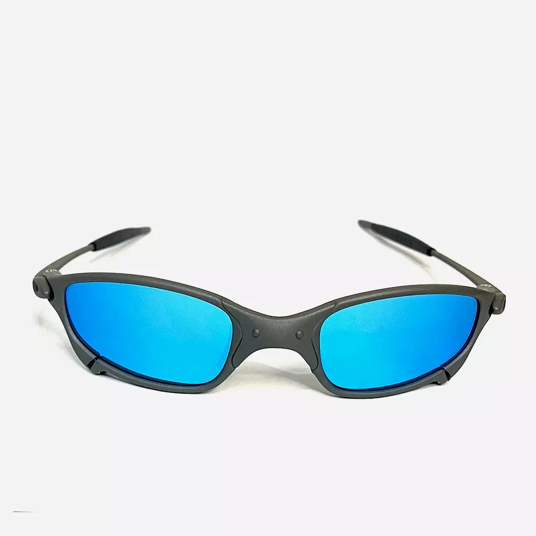 Óculos de sol Juliet com armação cinza fosca e lentes espelhadas em tom azul ciano, design esportivo e moderno. Modelo exclusivo da Lottus Unique, ideal para atividades ao ar livre e um visual contemporâneo.