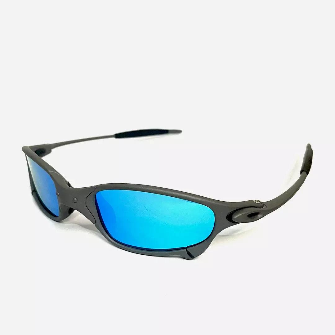 Óculos de sol Juliet com armação cinza fosca e lentes espelhadas em azul ciano, vista lateral que destaca o design aerodinâmico e esportivo. Modelo exclusivo da Lottus Unique, perfeito para um visual moderno e dinâmico.