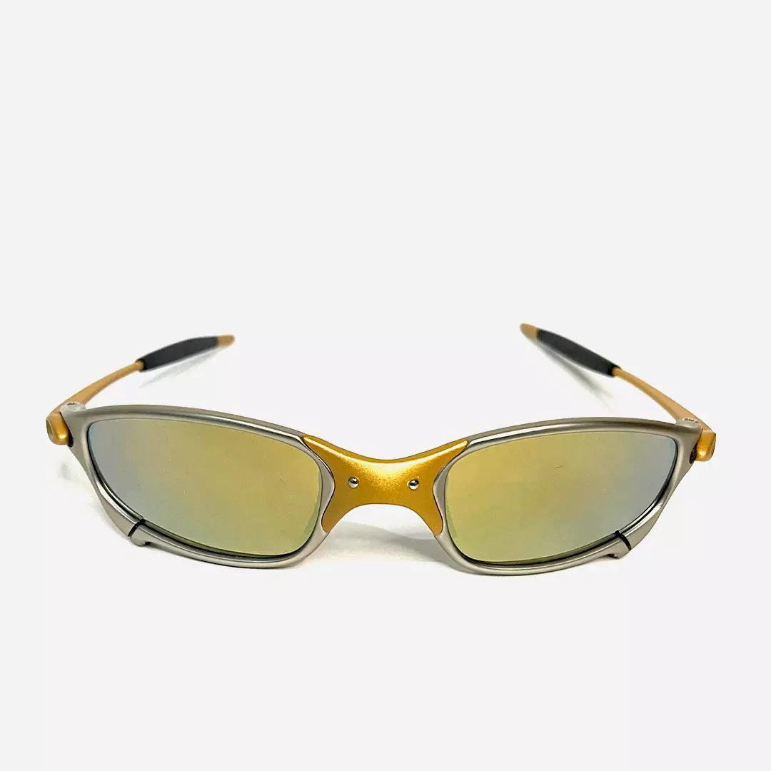 Óculos de sol Juliet com armação cinza e dourada, lentes espelhadas douradas, e design esportivo sofisticado. Modelo exclusivo da Lottus Unique, ideal para compor looks modernos e elegantes.