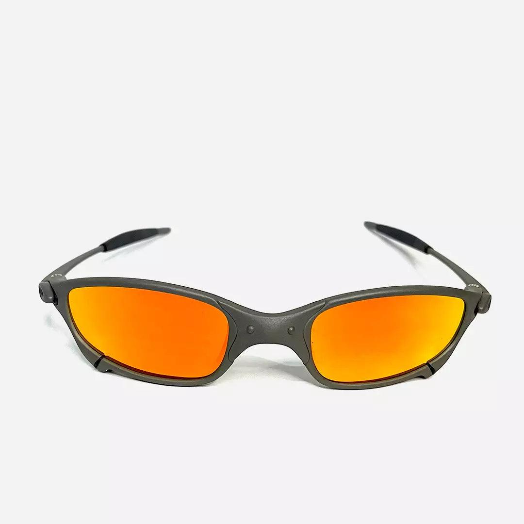 Óculos de sol Juliet com armação cinza fosca e lentes espelhadas laranja neon vistos de frente, destacando o design esportivo e moderno. Modelo exclusivo da Lottus Unique, ideal para um estilo arrojado e atividades ao ar livre.