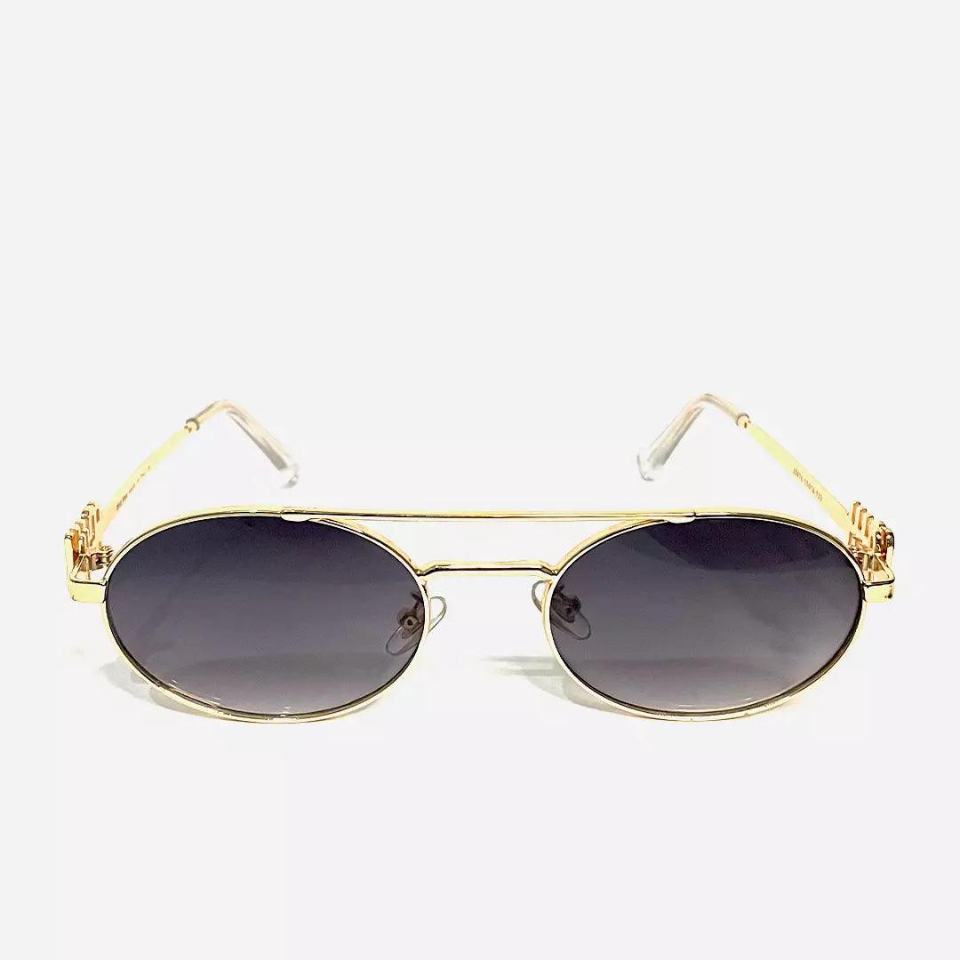 Óculos de sol Princess Gold com armação dourada elegante, lentes ovais em tom escuro e detalhes sofisticados nas hastes para um visual luxuoso e clássico.