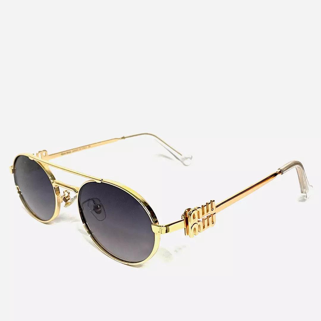 Óculos de sol Princess Gold com armação dourada brilhante e detalhes delicados nas hastes, combinados com lentes ovais escuras para um toque de sofisticação e glamour.