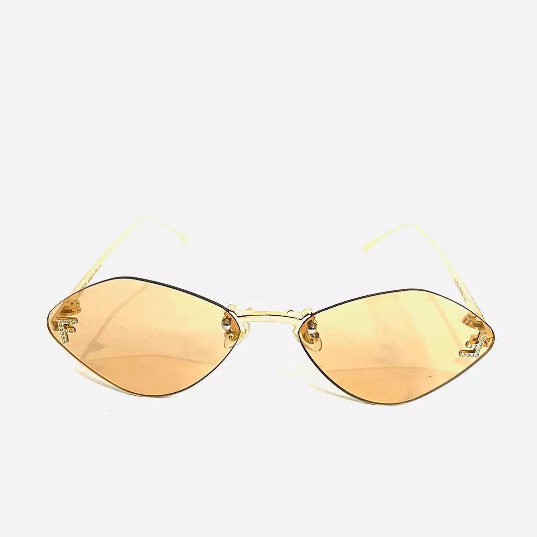 Óculos de sol Lucky Gold com armação leve e dourada, e lentes amareladas em formato geométrico, oferecendo um visual moderno e sofisticado.